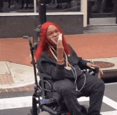 a woman with red hair is sitting in a wheelchair on the sidewalk