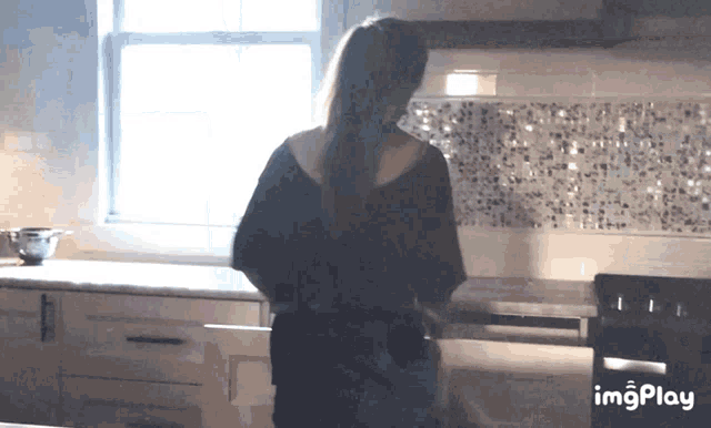 a woman is standing in a kitchen with imgplay written on the bottom of the screen