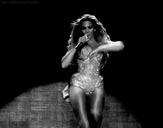 a black and white photo of a woman holding a microphone .
