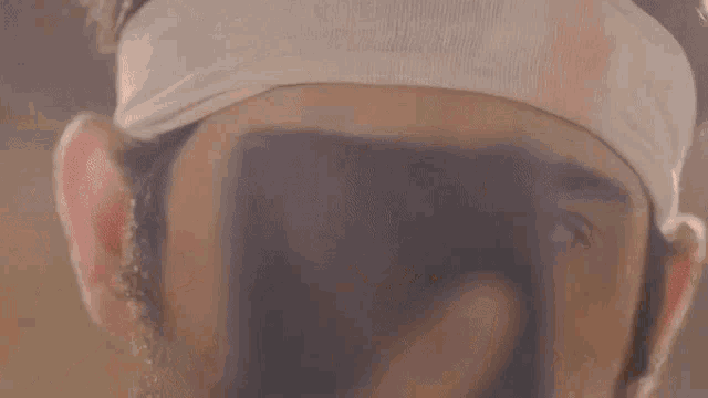 a man with a bandage on his head looks at a cell phone