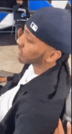 a man wearing a hat and a black jacket is sitting in a chair .
