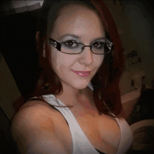 a woman wearing glasses and a white tank top looks at the camera