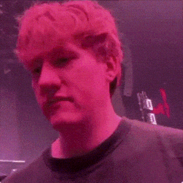 a close up of a man 's face with pink hair