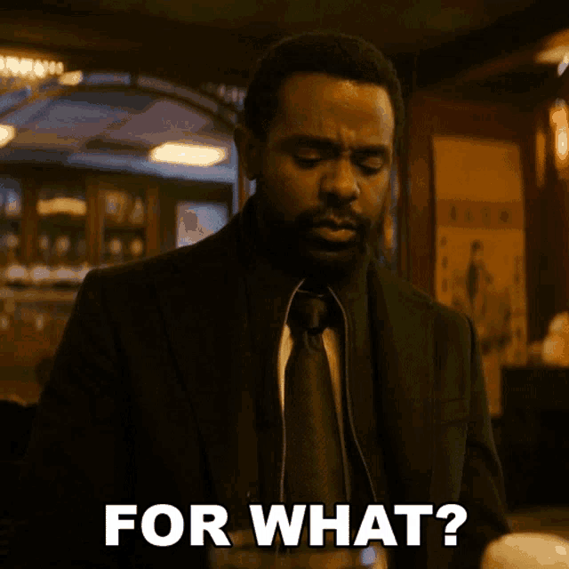 a man in a suit and tie is saying for what