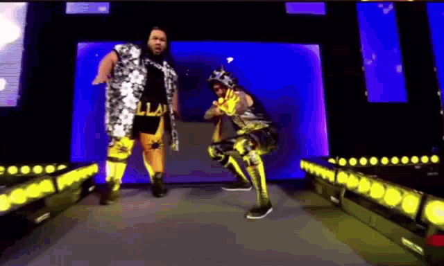 two wrestlers are standing on a stage and one of them has the word illa on his shirt