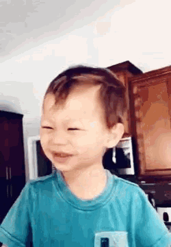 a young boy in a blue shirt is making a funny face .