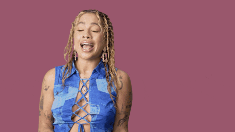 a woman in a blue shirt is standing in front of a pink background that says " yeah b * tch "