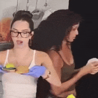 a woman wearing glasses and blue gloves holds a plate of food