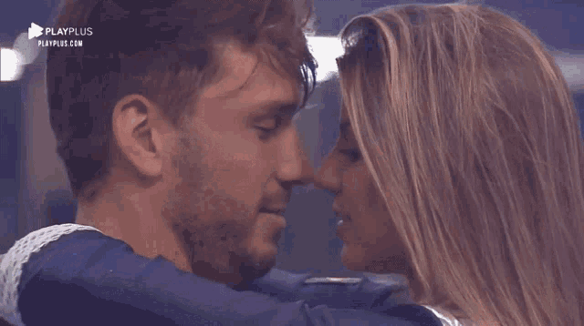 a man and woman are kissing in front of a playplus sign