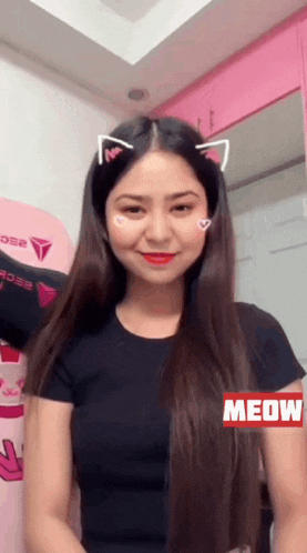 a woman with long hair and cat ears on her head is wearing a black shirt and smiling .