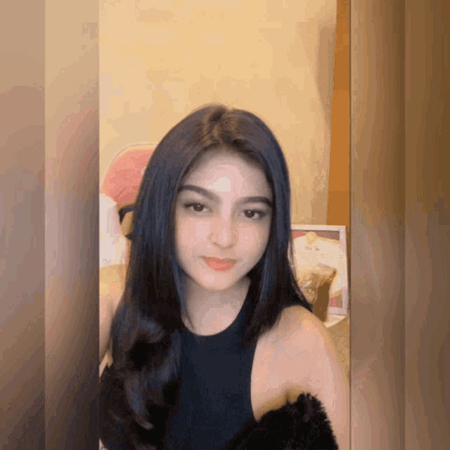 a woman with long black hair is wearing a black top