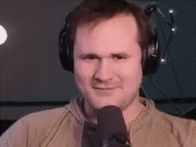 a man wearing headphones and a microphone is making a funny face