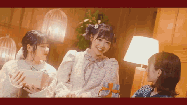 three girls are standing next to each other holding gifts and smiling