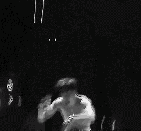 a black and white photo of a man without a shirt dancing on a stage .