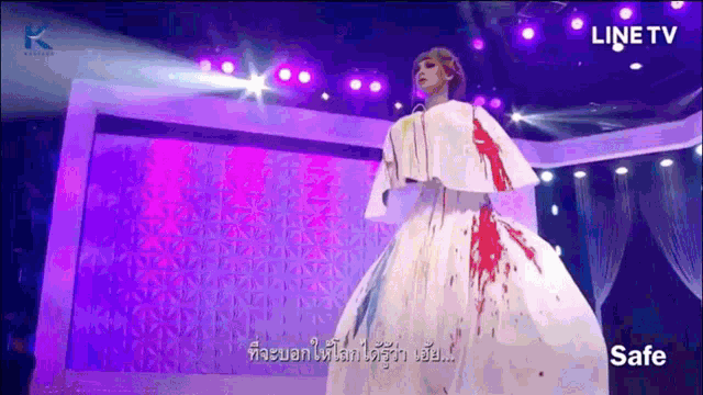 a woman in a white dress with blood on it is on a stage in front of a line tv logo