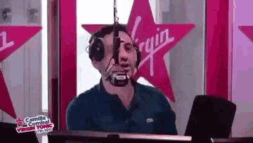 a man wearing headphones is talking into a microphone in front of a pink star .