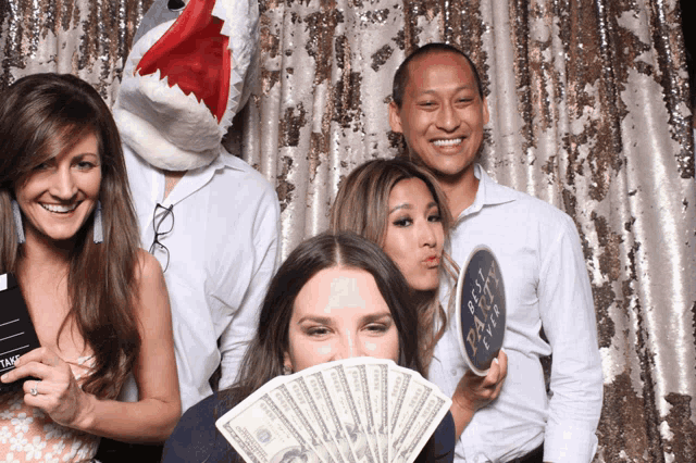 a group of people posing in a photo booth with one wearing a stuffed shark head