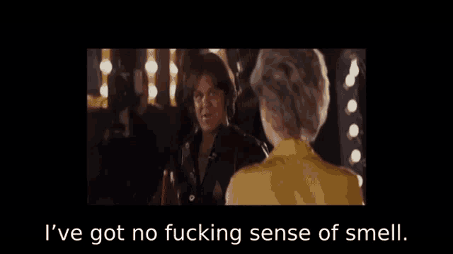 a woman in a yellow shirt talks to a man in a black jacket