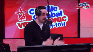 a man wearing headphones stands in front of a microphone at virgin radio