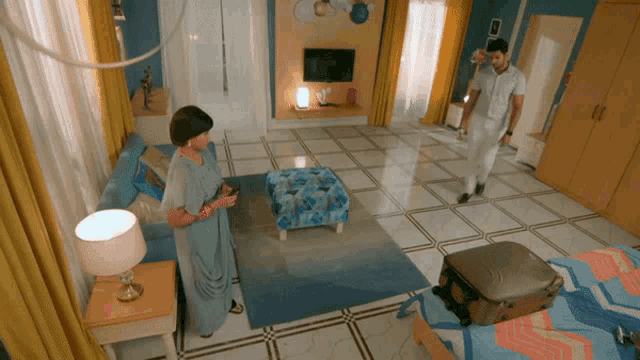 a man and a woman are standing in a living room with a suitcase on the floor