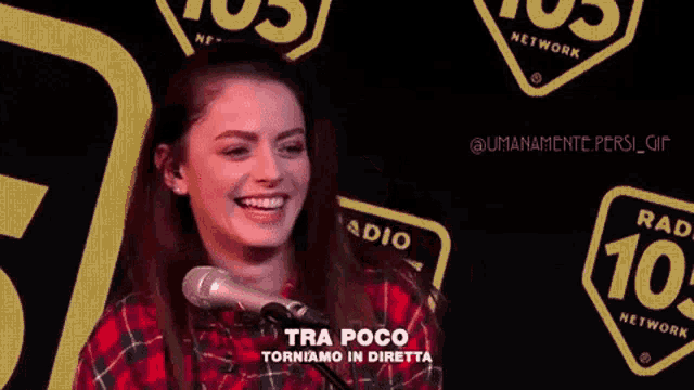 a woman stands in front of a microphone with the words tra poco written on the bottom