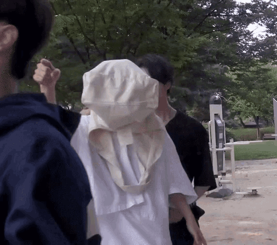 a person with a hood on their head is walking in a park .