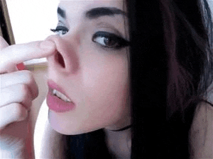 a woman is touching her nose with her finger .