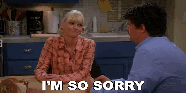 a man and a woman are sitting at a table and the woman is saying i 'm so sorry