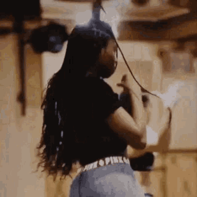 a woman with long hair is dancing in a room while wearing a black shirt and pink underwear .