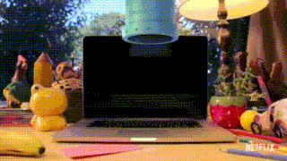 a laptop is sitting on a desk next to a lamp and a banana .