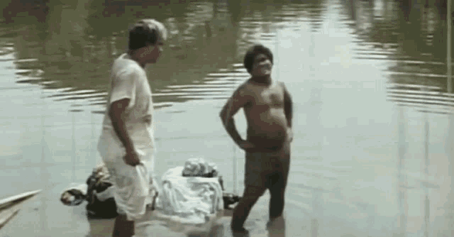 two men are standing in a body of water talking .