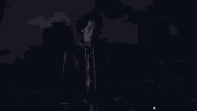 a man in a red jacket is standing in a dark room with a light coming out of his chest