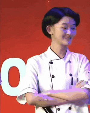 a woman in a chef 's uniform is standing with her arms crossed .