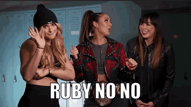 three women are standing next to each other in a locker room and one of them is wearing a wrestling belt .