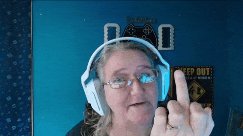 a woman wearing headphones is giving the middle finger in front of a keep out sign