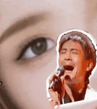 a man singing into a microphone in front of a woman 's face