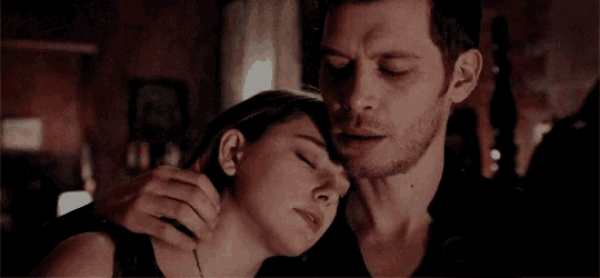 a man is touching a woman 's neck while they are laying down .