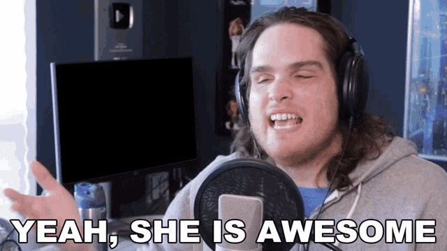 a man wearing headphones singing into a microphone with the words " yeah she is awesome " below him