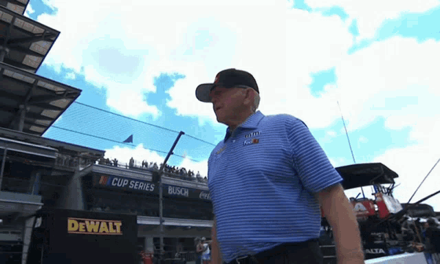 a man in a blue shirt stands in front of a dewalt sign