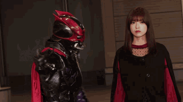 a woman is standing next to a man in a costume with a red cape that says ' x ' on it