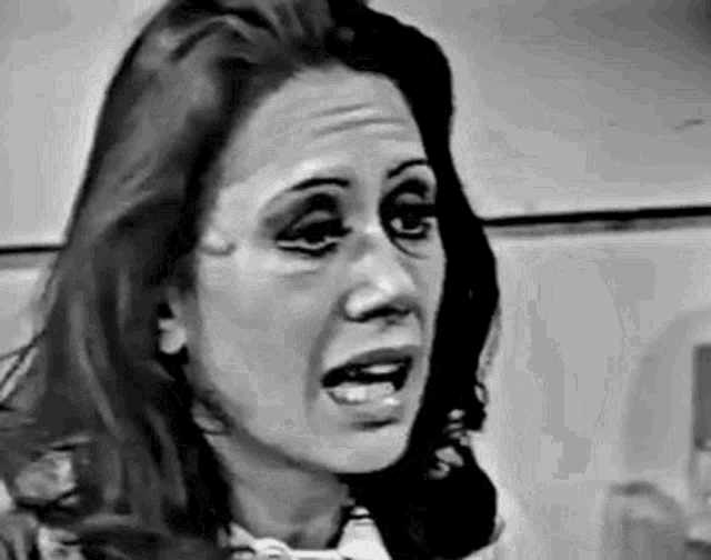 a black and white photo of a woman making a funny face with her mouth open .