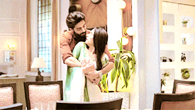 a man with a beard is hugging a woman in a living room .