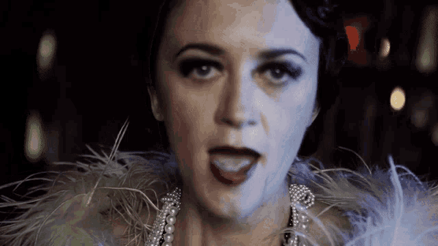 a woman is wearing a pearl necklace and a feather collar