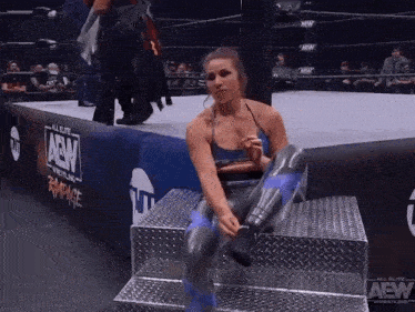 a woman in a wrestling ring is sitting on a metal platform .