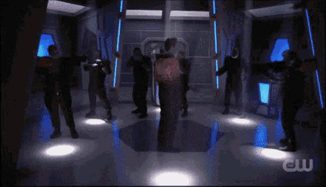 a group of people are standing in a room with a cw logo on the bottom