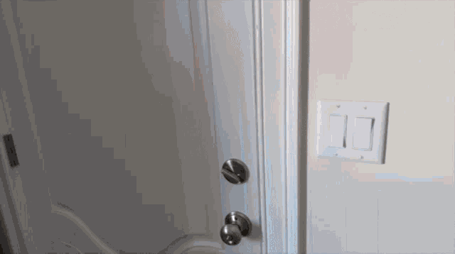 a person is opening a door with a light switch in the background