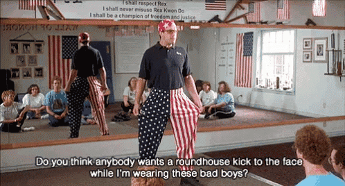 a man in red white and blue striped pants stands in front of a group of people in a gym