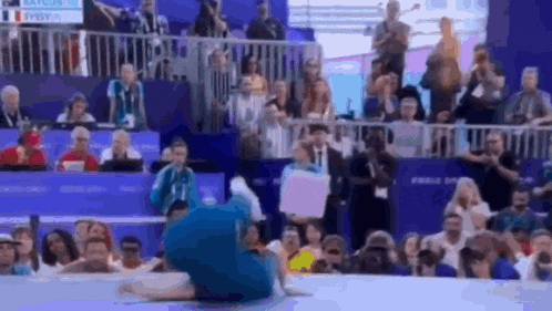 a gymnast is doing a trick in front of a crowd with a sign that says ' swiss ' on it