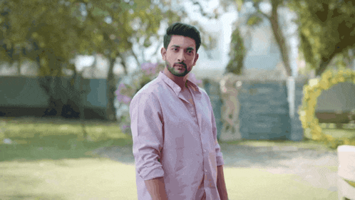 a man in a pink shirt is standing in the grass