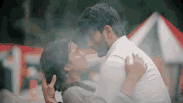 a man is holding a woman in his arms while they kiss .